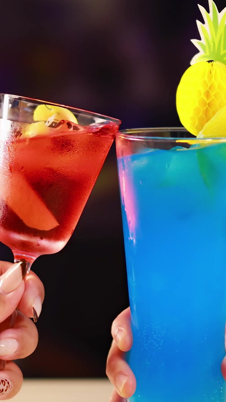 Two vibrant cocktails clink in a lively bar setting, highlighting colorful drinks and festive atmosphere with dynamic lighting