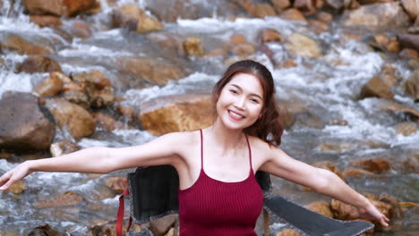 휴가 여름에 휴식과 행복을 위해 큰 바위와 물이 천천히 튀는 의자에 앉아 빨간색으로 아시아 여자