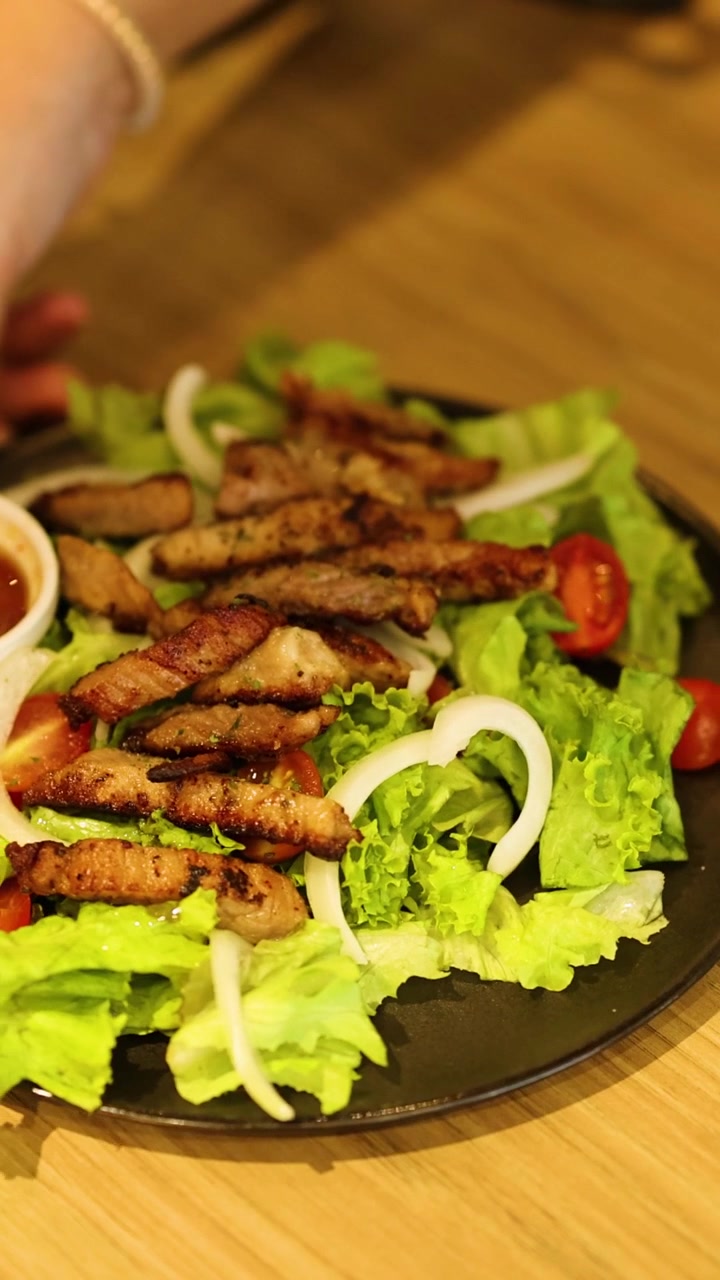 Mani che preparano un'insalata di maiale con salsa
