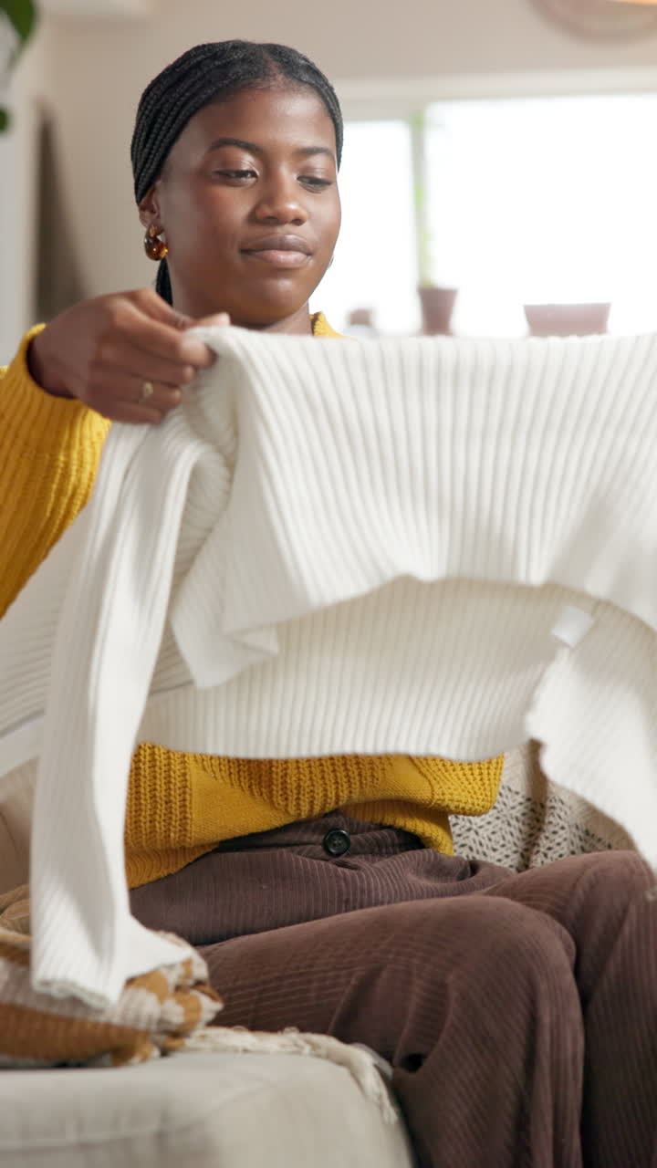 Woman folding sweaters on couch
