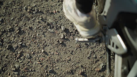 close-up of a person s foot removing the kickstand from a motorcycle and pressing on the gear lever to move the bike forward