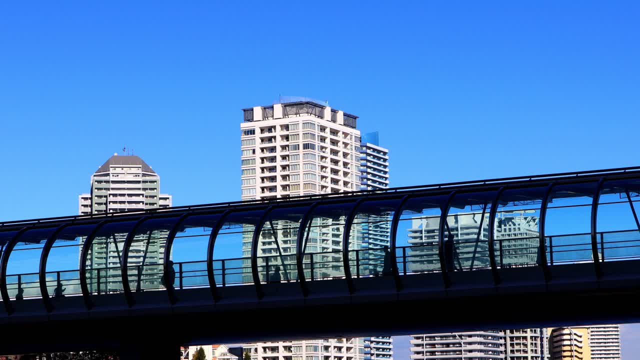 Silhouette di persone che camminano sul ponte con un condominio sullo sfondo