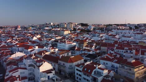 aerial establishing shot of waterfront village of ericeira, a surfing town in portuguese coastline, pullback shot