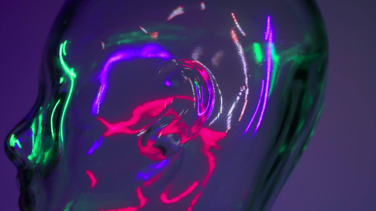 cabeza de vidrio girando como si estuviera en exhibición bajo múltiples luces de colores