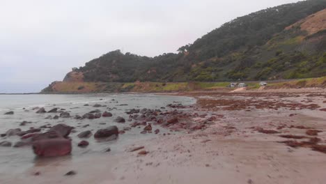 Dron-Aéreo-De-Bajo-Vuelo-Sobre-Una-Playa-Rocosa-Y-Húmeda-En-Una-Mañana-Brumosa