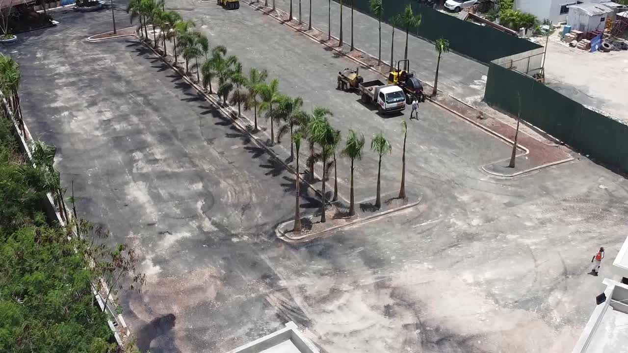 카펫을 깔기 위해 땅을 준비하기 위해 액체를 퍼뜨리는 노동자들을 보여주는 공중 드론 샷