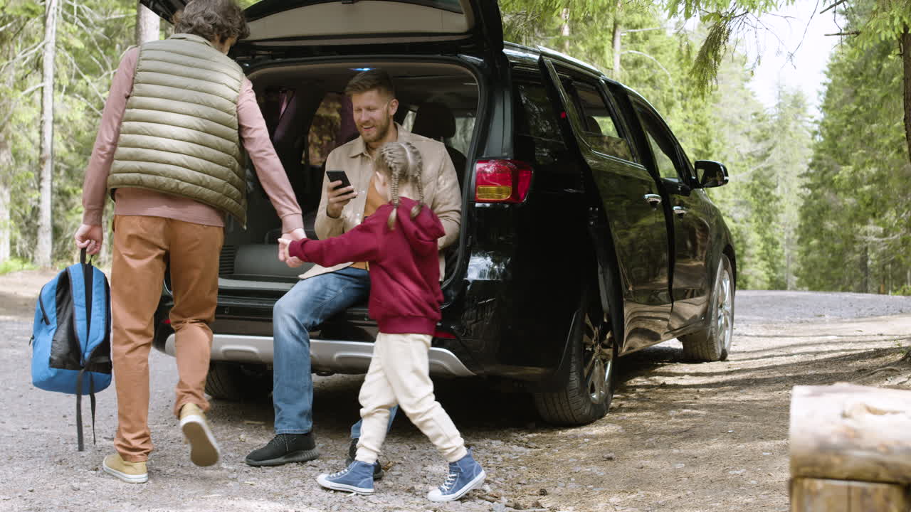 familia alrededor de un gran coche negro en el bosque