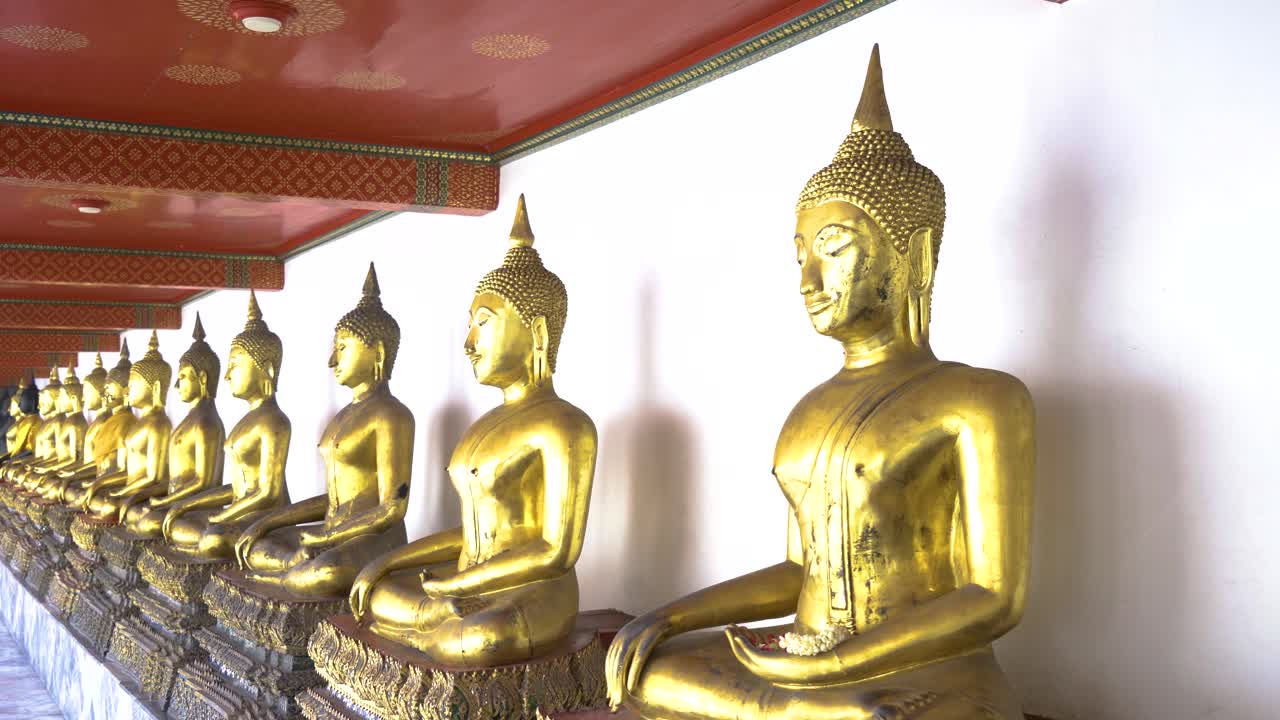 una fila de esculturas doradas de buda en un templo en tailandia