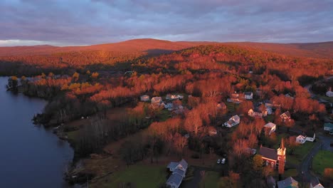 aerial orbit around shore line of rural lake with golden hour light on late fall bare trees