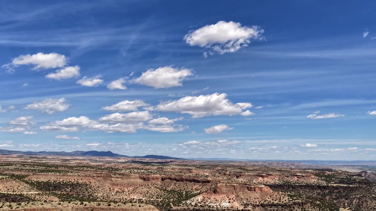 En filmisk 4K drone-timelapse fanger lag af små, bløde skyer, der bevæger sig over sydvestlige mesaer i levende lys. Denne dynamiske vejrovergang skaber en episk naturbaggrund til B-roll.
