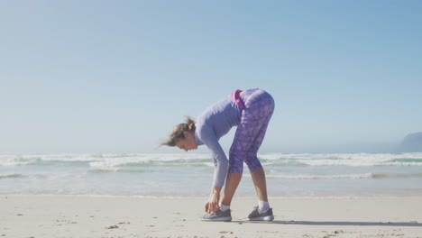 Mujer-Atlética-Atando-Sus-Zapatos-En-La-Playa