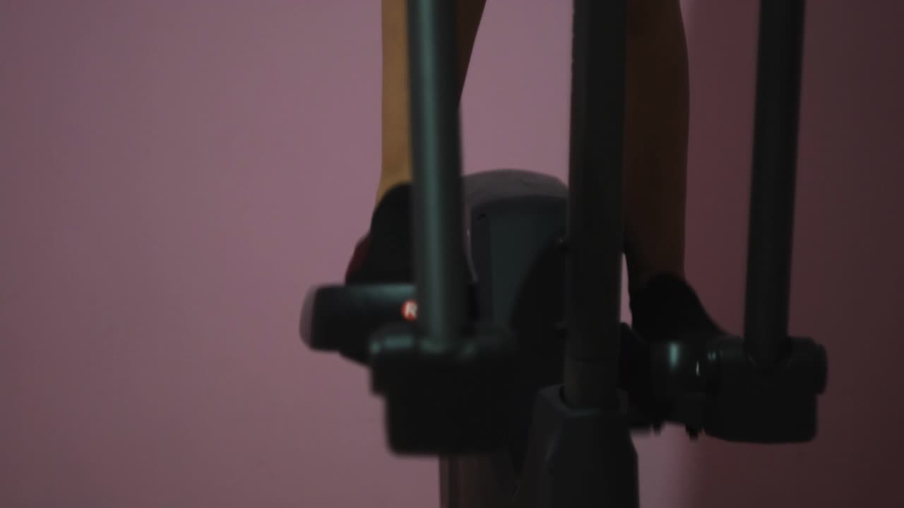 persona que hace ejercicio en una máquina elíptica en un gimnasio