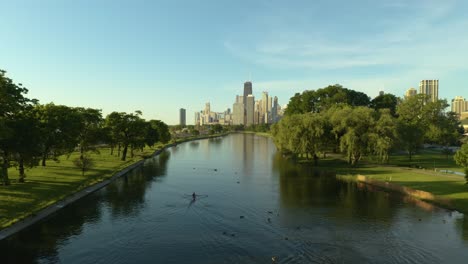 Antena,-Gente-Remando-Con-El-Horizonte-De-Chicago-En-El-Fondo-Durante-La-Hermosa-Tarde-De-Verano