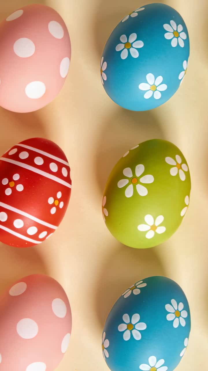 Vertical video: Camera panning on beige surface, reframing polka-dot and daisy eggs for design