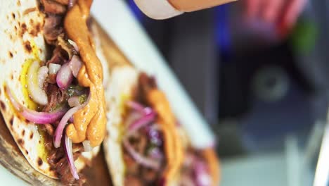 chef seasoning some meat and vegetable tacos with sauce