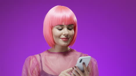 pretty woman wearing a pink wig tapping and texting a message on her smartphone