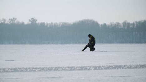 pescador de silueta sobre el hielo en un lago congelado en invierno