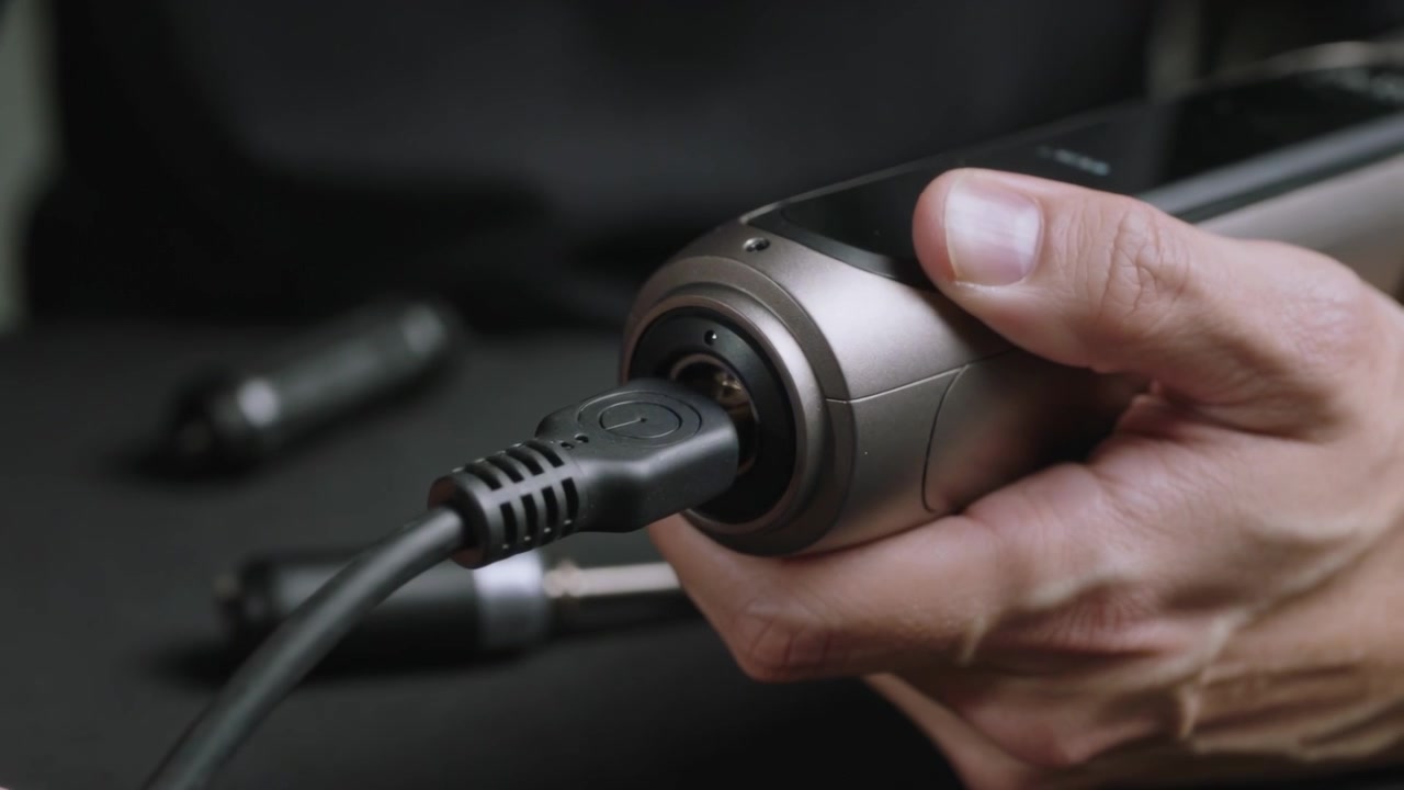 Aligning hands inserting adapter into metal device on bench, plugging cable making blue LED glow