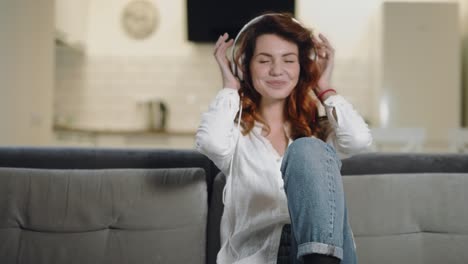 smiling woman sitting at open kitchen in headphones.