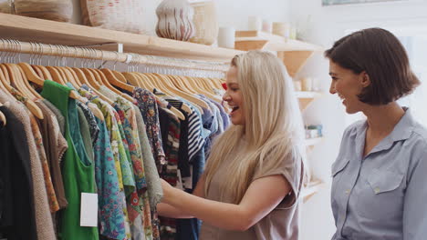 sales assistant in fashion store helping female customer to choose clothing dress from rail