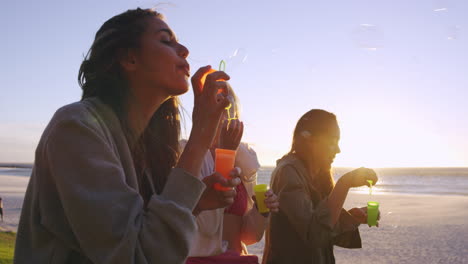 Girl-friends-blowing-bubbles-on-beach-at-sunset-slow-motion