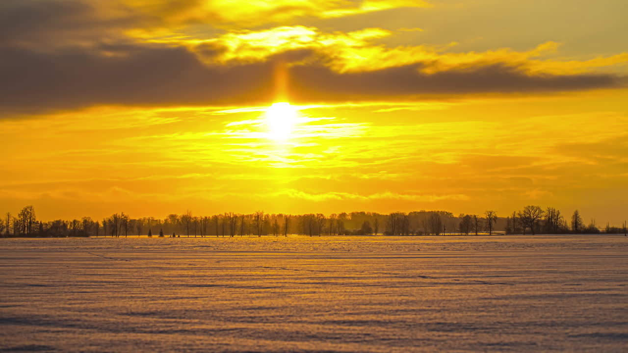 таймлапс сказочного зимнего пейзажа со снежным лугом и деревьями под желто-оранжевым солнцем
