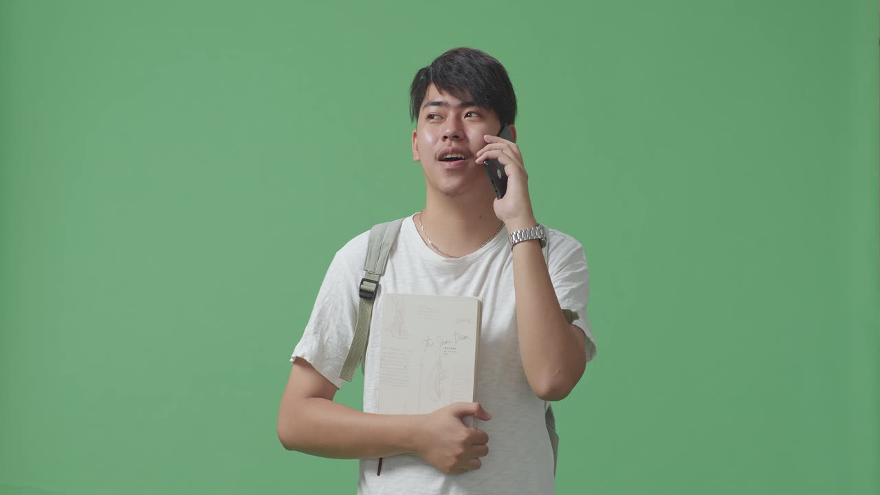 estudiante asiático hablando por teléfono móvil en el estudio de pantalla verde