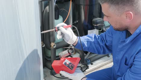 el técnico repara los sensores electrónicos de temperatura con un soldador electrónico