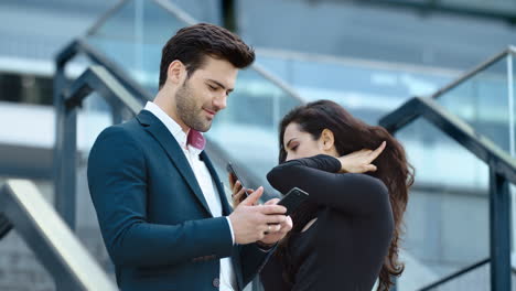 Closeup-couple-using-phones-at-street.-Coworkers-talking-together-at-street