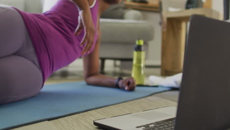 happy african american wearing sportswear, exercising, using laptop