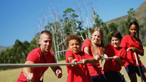 trainer assisting kids in tug of war during obstacle course training