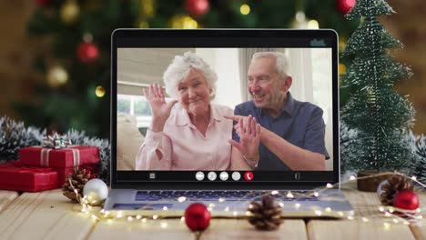 Caucasian-senior-couple-waving-on-video-call-on-laptop,-with-christmas-tree