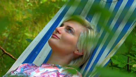 una mujer relajándose bajo el sol en una cama de árbol oscilante para dormir en la naturaleza con una actitud positiva