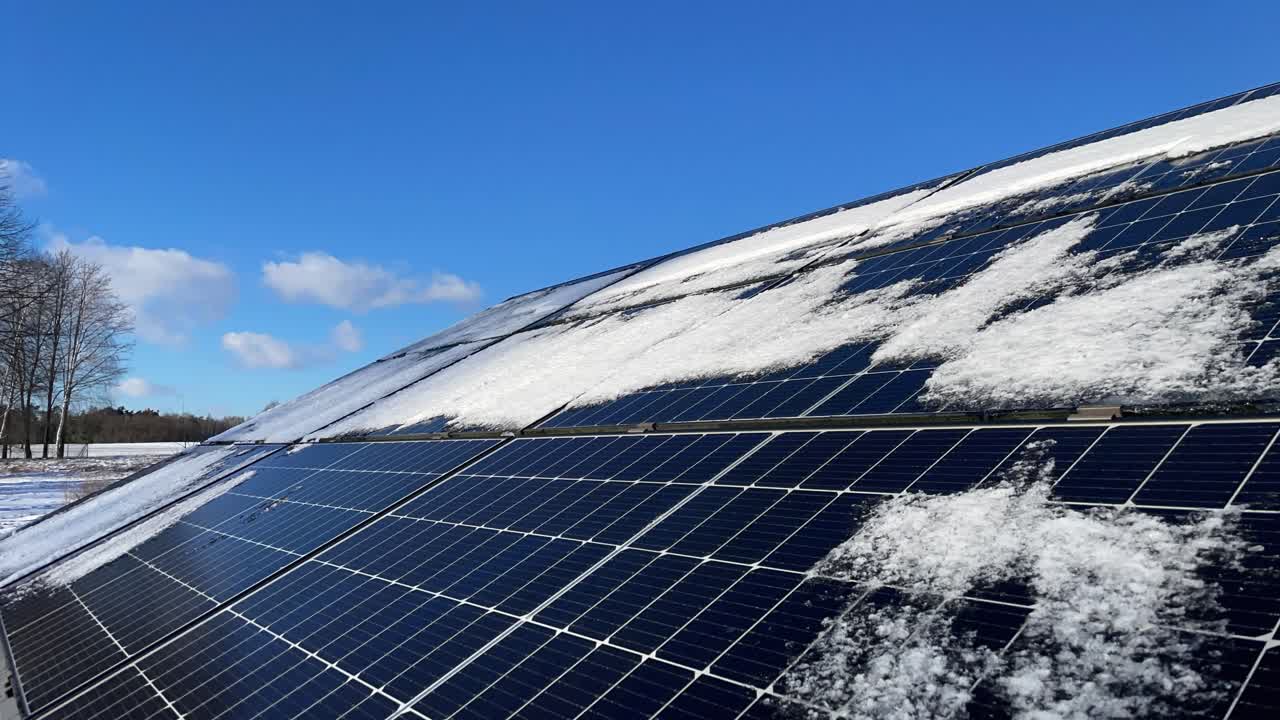 Timelapse di un pannello fotovoltaico mentre la luce del sole scioglie la neve rimanente e le nuvole corrono nel cielo, rivelando gradualmente la superficie