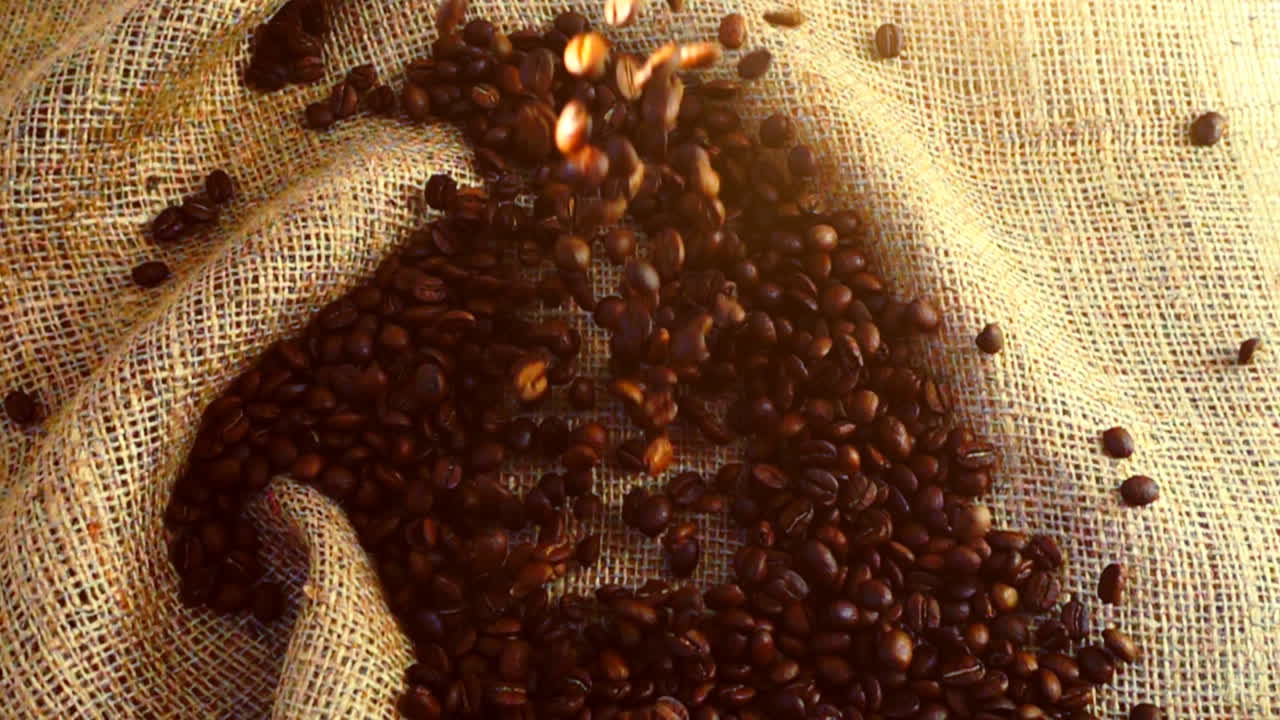 Grãos de café caindo sobre estopa. Câmera lenta.