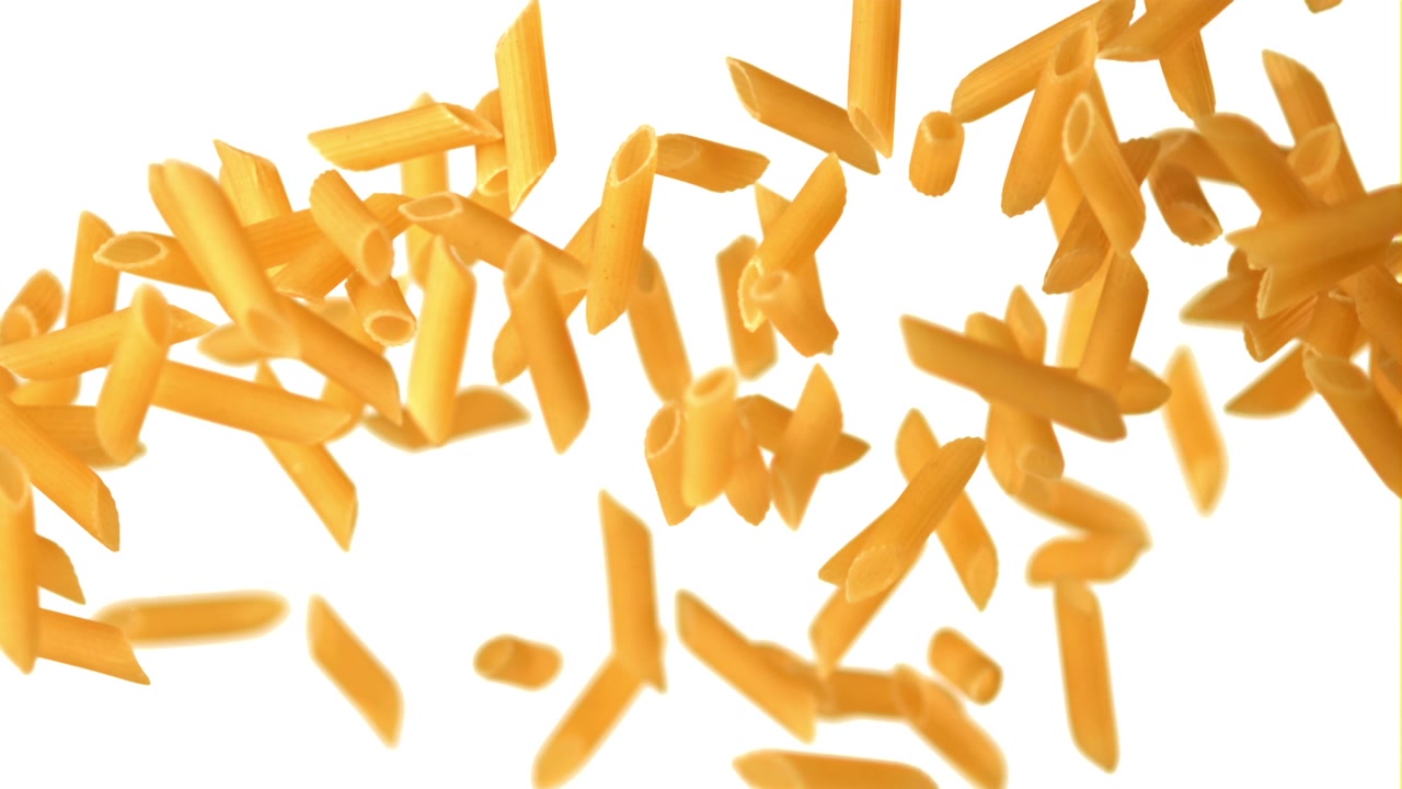 Pasta penne cruda che cade e galleggia su uno sfondo bianco.