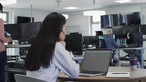 Asian woman sitting at desk coding data on laptop