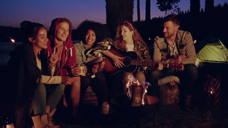 amigos acampando por la noche junto a la hoguera
