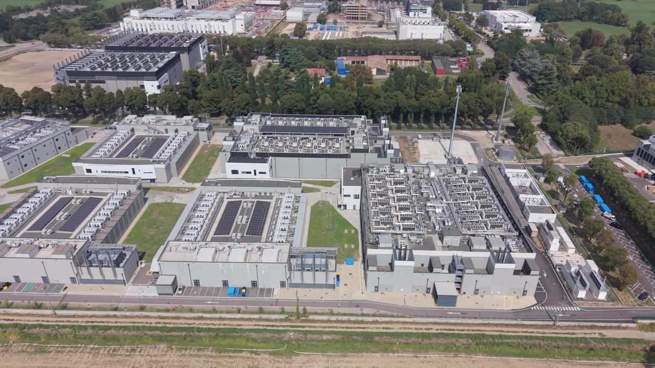 Vista aerea del Campus DATA4 di Milano, che evidenzia grandi strutture tecnologiche, apparecchiature di raffreddamento sul tetto e installazioni solari. Adatto per storie visive sull'informatica AI