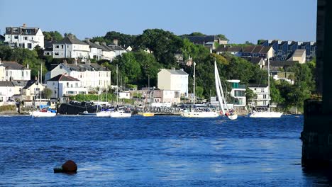 a sailboat sailing down the river tamar with plymouth in the background between devon and cornwall