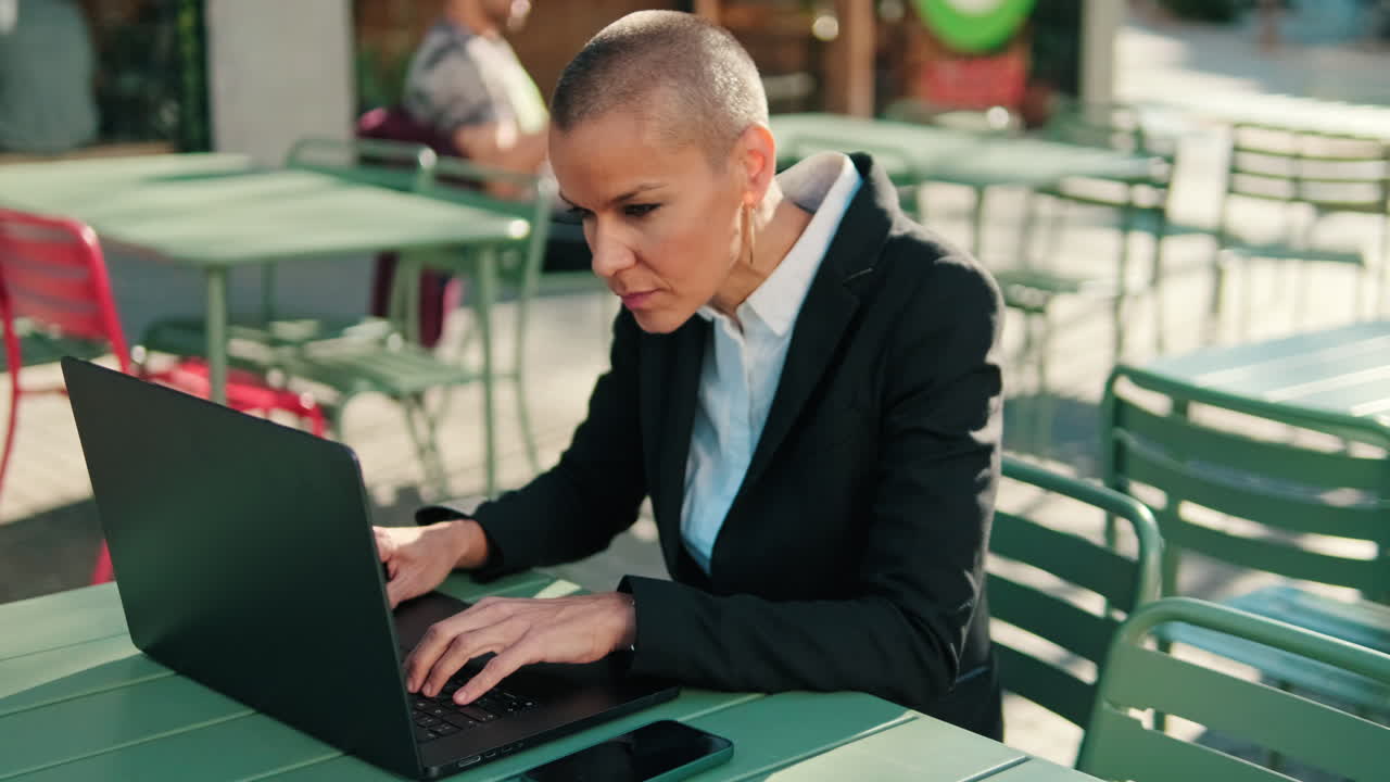 Focused Businesswoman Typing on Laptop at Outdoor Cafe