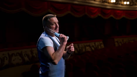actor puts facial mask off and annonces beginning of thater season beginning. happy man on stage.