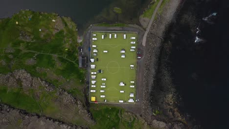 Football-pitch-used-as-campsite-on-Faroe-Islands-coast,-aerial-birds-eye-view