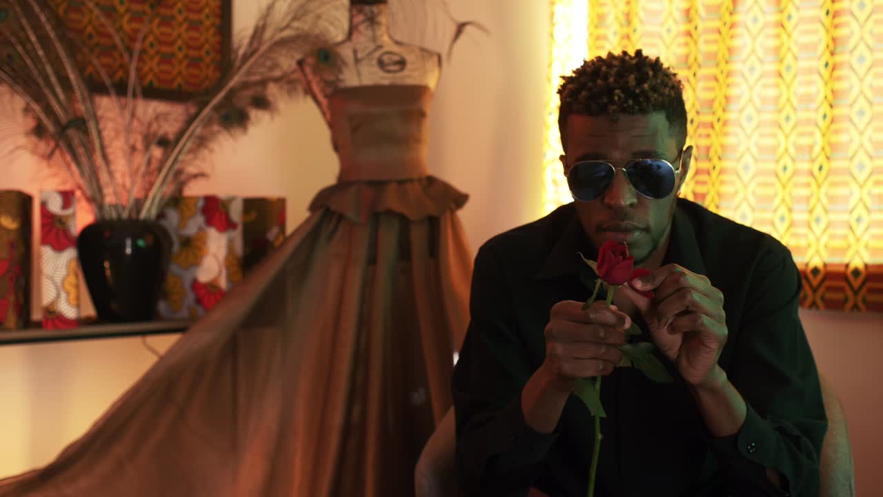 Stylish french man plucking rose petals with cold facial expression, medium shot