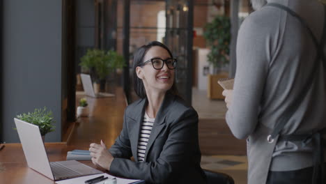 businesswoman having a conversation with a waiter in a modern office cafe.
