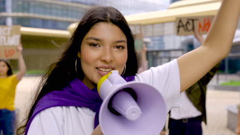 donna castana che grida su un megafono e rallegra i suoi colleghi sulla protesta