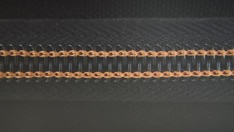 a macro close-up shot of a hard case zipper being opened, orange yellow strings, metal zip, black box, photography gear, professional studio lighting, static 4k video