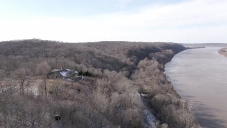 Aerial-Drone-Footage-Dollying-Forward-Alongside-a-River-Past-an-Abandoned-Lodge