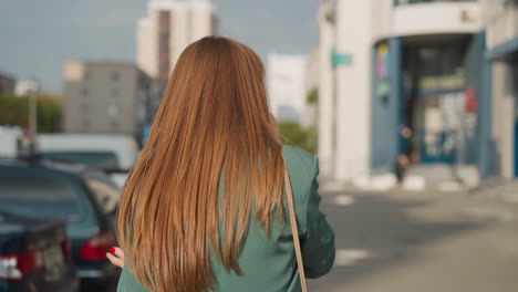 mujer habla por teléfono móvil caminando por el aparcamiento de la ciudad