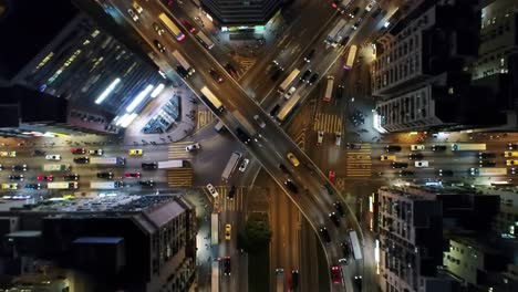 bright lights illuminate a bustling urban intersection at night, showcasing the dynamic flow of vehicles. the aerial perspective highlights the organized chaos of city traffic and city life.